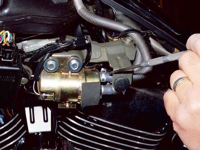 To check fuel flow when a remote tank/pump is used, locate the fuel pump. This one is located under the side cover. Remove the discharge side hose—that's the one from the pump to the carburetor.