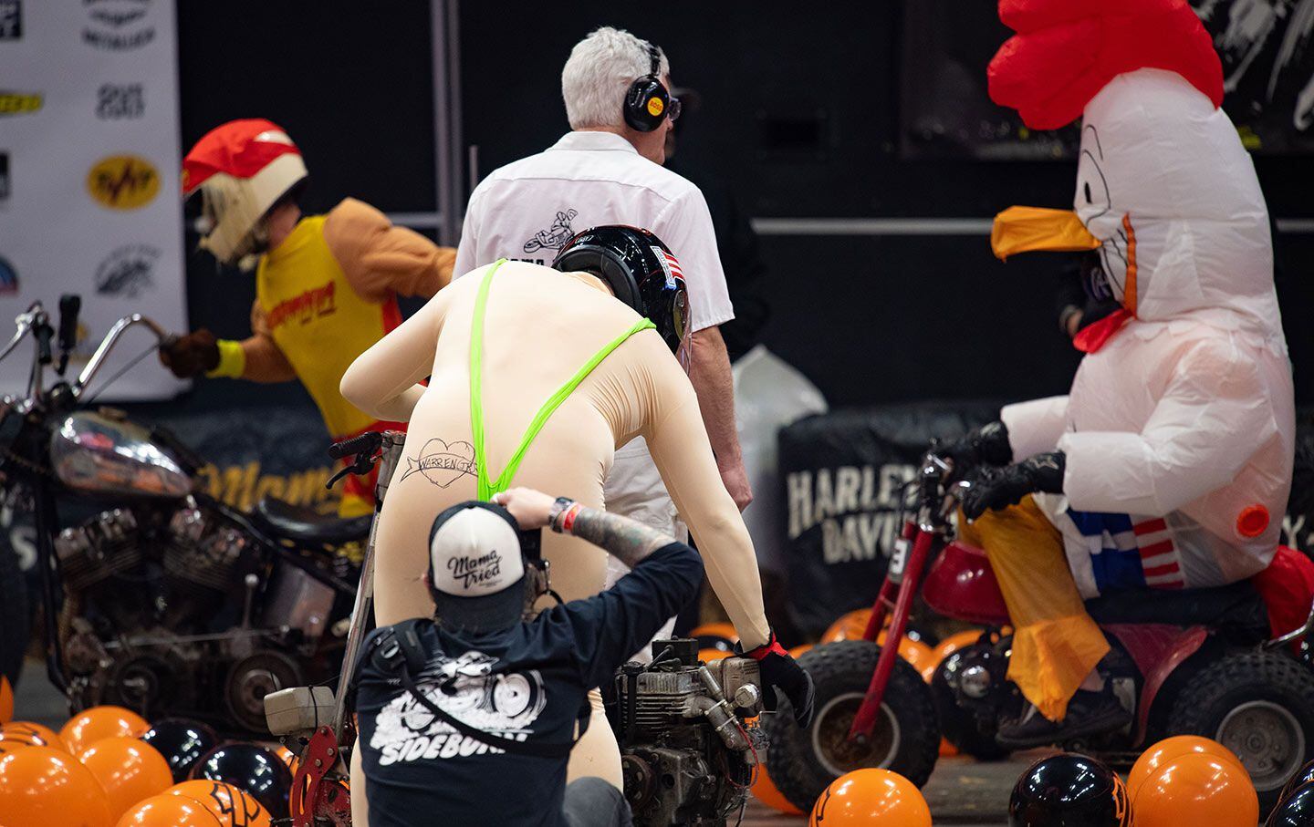 An unidentified Borat-inspired racer pull-starts his Boonie class bike, with Chicken Fried Rick looking on.